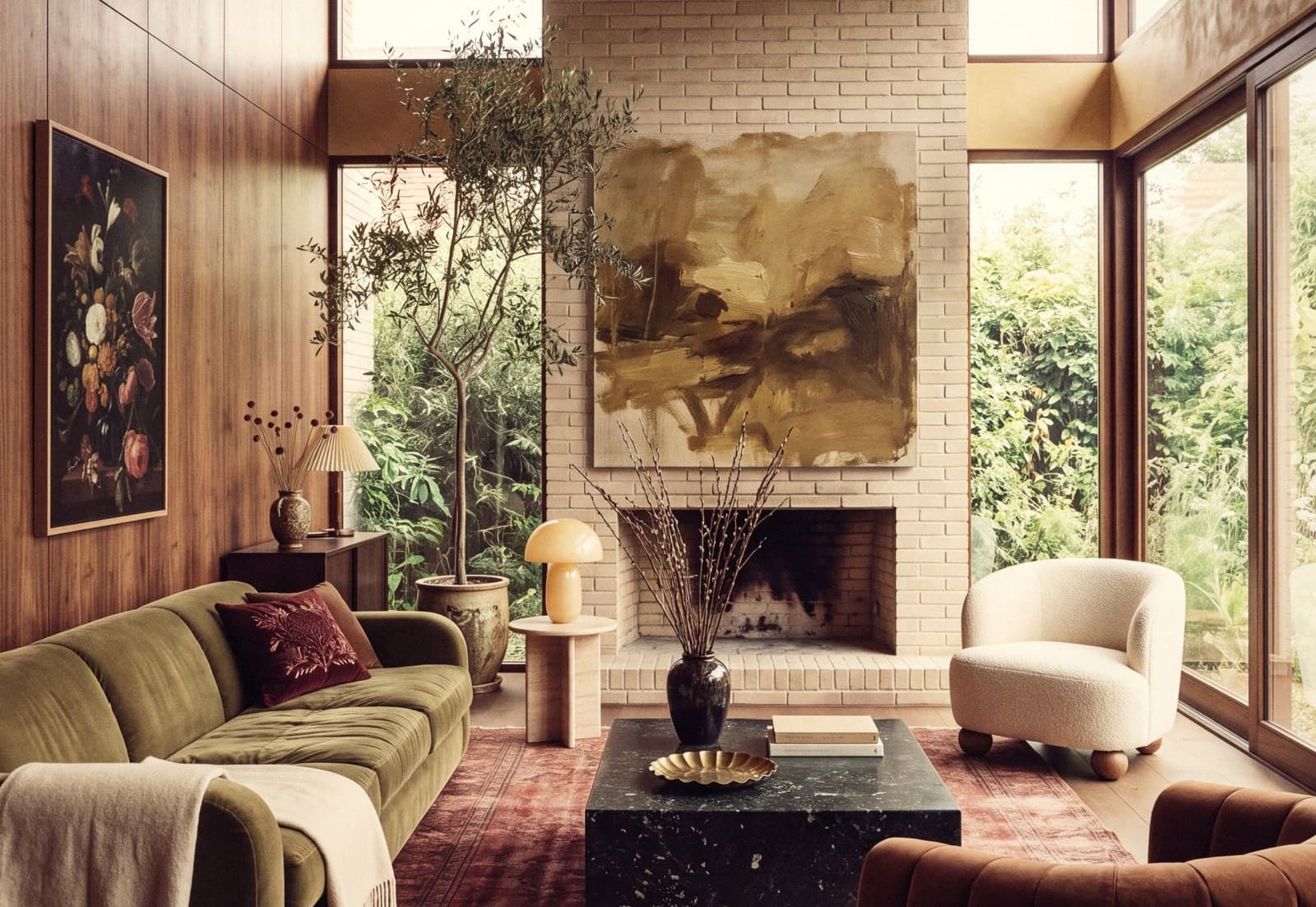 Living room with walnut panelling, a pale brick fireplace, an olive velvet sofa and a worn red rug